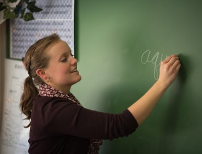 3rd grade teacher using chalkboard to instruct