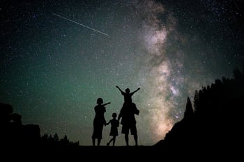 Happy family silhouette with Milky Way and beautiful night sky full of stars in background