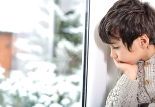 Sad kid on window cannot go out because of cold and snow.jpeg