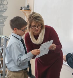 boy-looking-at-paper-with-teacher