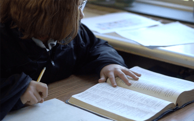 student in robe reading bible